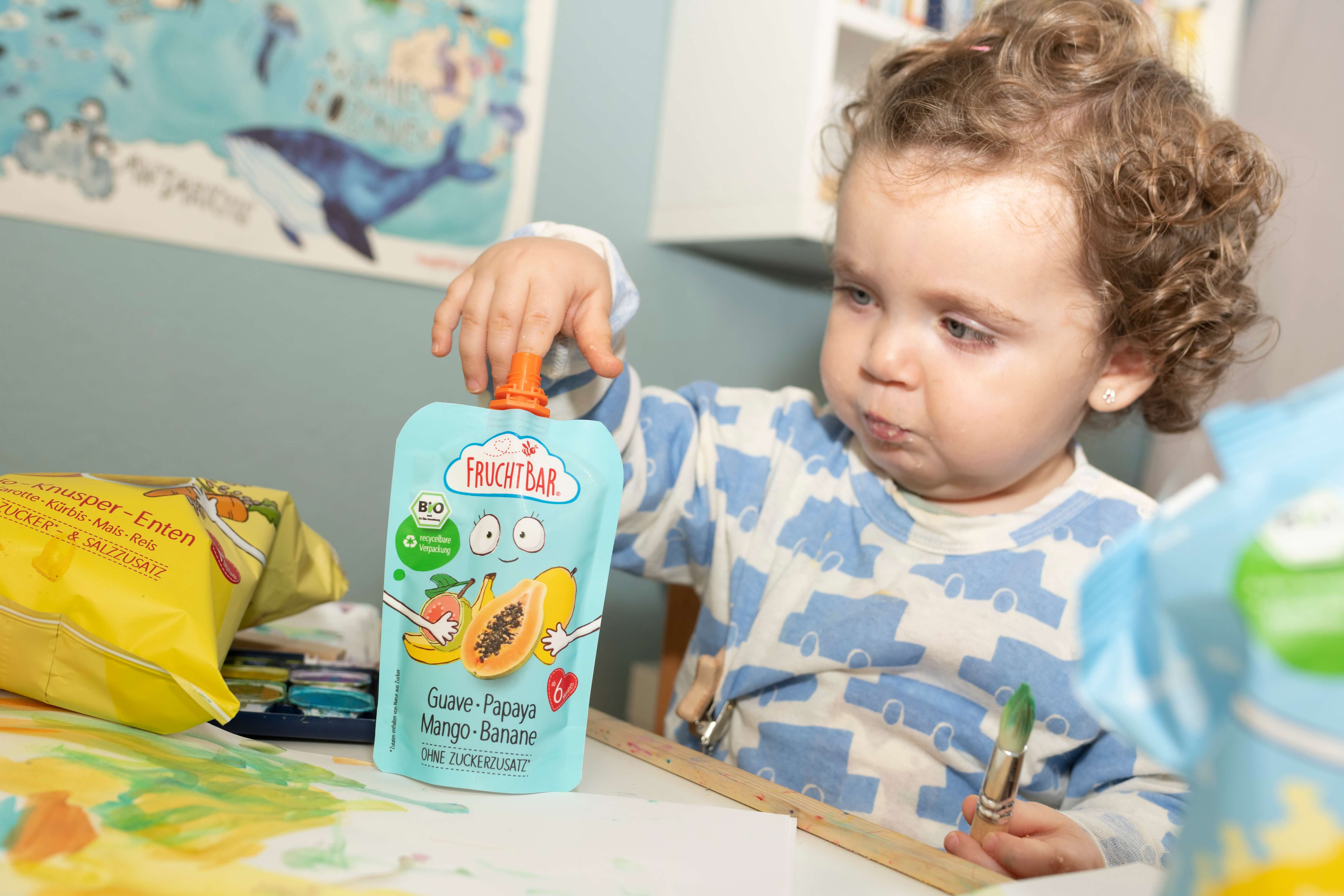 FruchtBar Bio Quetschie für Baby Baby am Tisch mit FruchtBar Bio Quetschie