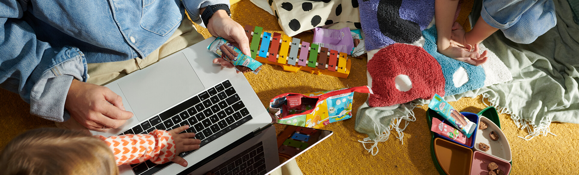 Kinder und Vater spielen im Zimmer und essen FruchtBar Riegel
