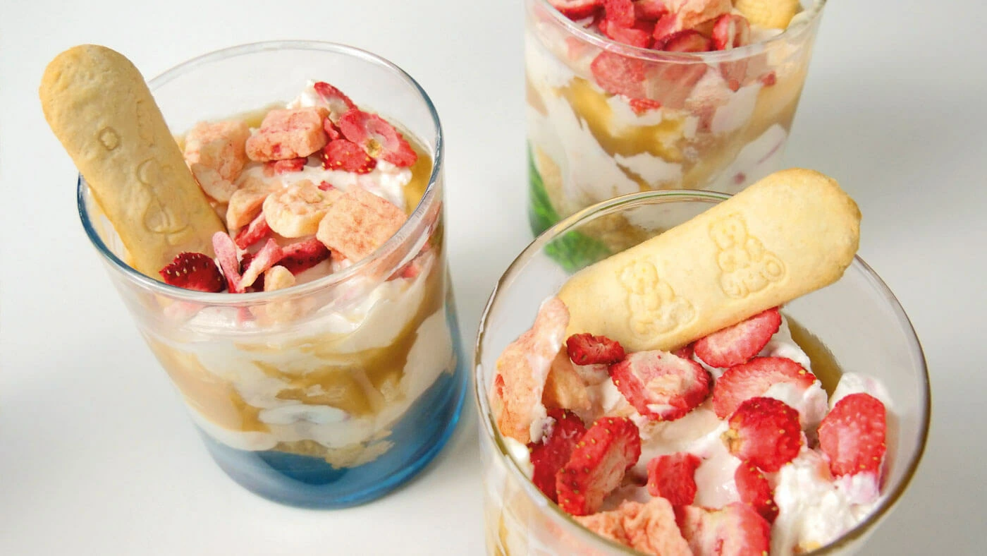 Creme Dessert mit Erdbeeren udn Sahne, dazu Fruchtbar baby Keksriegel. Serviert in Gläsern