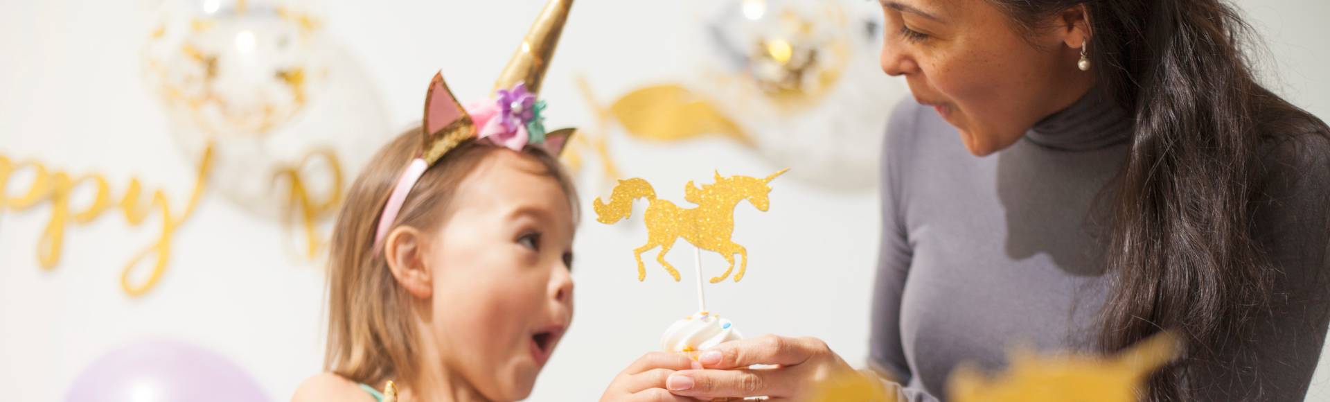 Einhorn Kindergeburtstag Geburtstagskind efreut sich über Einhorn Cupcakes