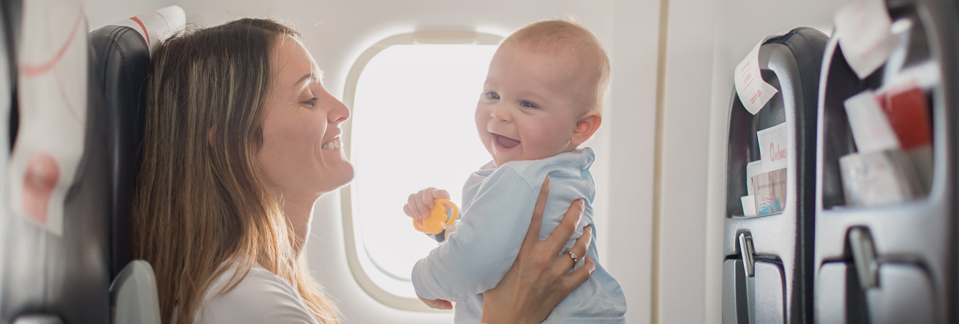 Mutter und Baby lächelnd im Flugzeug